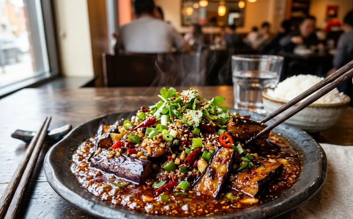 Spicy garlic eggplant in red chili sauce topped with green onions, sliced chilies and cilantro